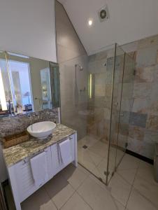 a bathroom with a sink and a glass shower at Waterfront Maison by Simply-Seychelles in Eden Island