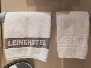 twee handdoeken hangend aan een handdoekenrek in een badkamer bij Leine Hotel in Pattensen