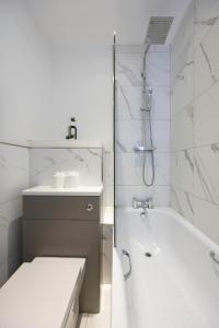 ein weißes Badezimmer mit einer Badewanne und einem Waschbecken in der Unterkunft Stunning Two Bedroom Brighton Penthouse in Brighton & Hove