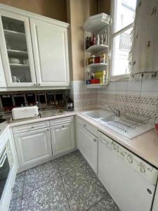 a kitchen with white cabinets and a sink at Les Jardins de l'Opéra - Elegant - Spacieux in Paris