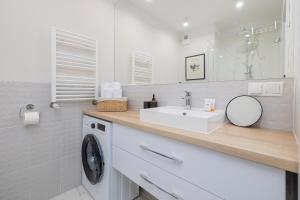 a white bathroom with a sink and a washing machine at Modern Studio with Garden in Świnoujście by Renters in Świnoujście