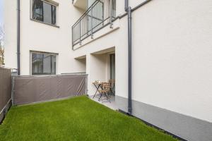 Un pequeño patio trasero con césped verde al lado de un edificio blanco. en Modern Studio with Garden in Świnoujście by Noclegi Renters, en Świnoujście