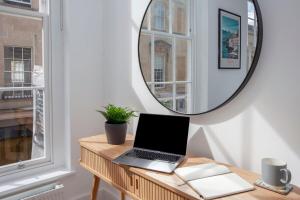 a laptop on a wooden table in a room with a mirror at ※ Stunning Apt - Centre of Historic Bath ※ in Bath