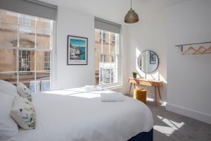a white bedroom with a bed and a desk and windows at ※ Stunning Apt - Centre of Historic Bath ※ in Bath