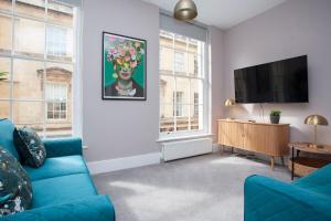 a living room with a blue couch and a flat screen tv at ※ Stunning Apt - Centre of Historic Bath ※ in Bath +35 photos