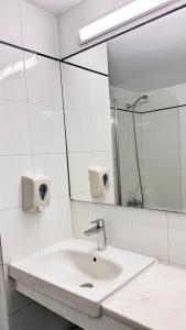 W białej łazience znajduje się umywalka i lustro. w obiekcie Navarria Blue Hotel w mieście Limassol