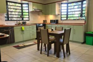 a kitchen with green cabinets and a table and chairs at Comfortabele vakantiewoning in Wanica, Suriname in Wanica