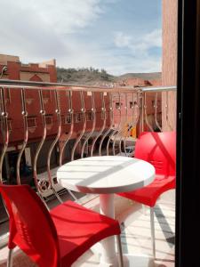 uma varanda com uma mesa branca e cadeiras vermelhas em DIAAFATE TANNIRTE em Khenifra