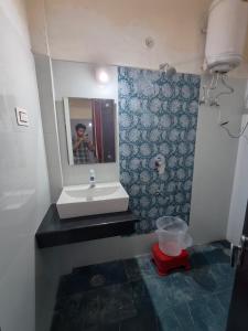 a man taking a picture of a bathroom with a sink at AASHIRWAD HOTEL in Katra
