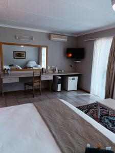 a bedroom with a bed and a desk in a room at Pecan Farm Guesthouse in Louis Trichardt