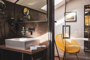 a bathroom with a white sink and a yellow chair at Villa Sonnenhof Boutique-Hotel in Bad Reichenhall