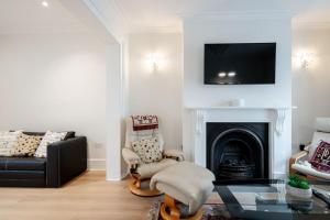 een woonkamer met een zwarte bank en een open haard bij Luxury 3BRs house in the heart of Victoria in Londen