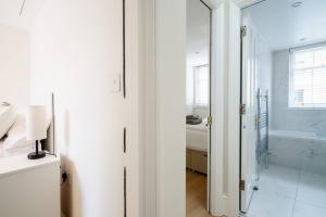 een witte badkamer met een glazen deur naar een slaapkamer bij Luxury 3BRs house in the heart of Victoria in Londen