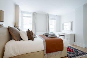 een slaapkamer met een groot bed met witte muren en ramen bij Luxury 3BRs house in the heart of Victoria in Londen