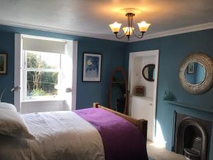 Mansefield Rooms في لوكربي: غرفة نوم بجدران زرقاء وسرير ومرآة