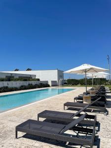 a swimming pool with lounge chairs and an umbrella at Masseria Giovanni in Martano