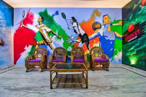 une peinture murale dans une pièce avec des chaises et une table dans l'établissement OYO Atithi Bhawan, à Jamshedpur