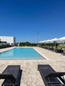 una piscina con bancos y sombrillas en un complejo en Masseria Giovanni, en Martano