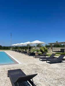 una fila de sillas y sombrillas junto a una piscina en Masseria Giovanni, en Martano