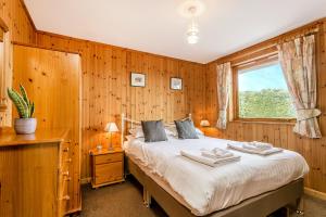 a bedroom with a bed with wooden walls and a window at Holly Lodge 4 Bedrooms Minehead in Minehead