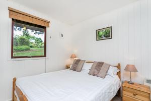 ein weißes Schlafzimmer mit einem Bett und einem Fenster in der Unterkunft Laburnum Lodge in Minehead