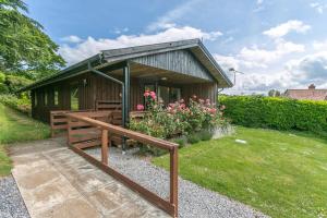 ein kleines Holzgebäude mit einer Bank und Blumen in der Unterkunft Laburnum Lodge in Minehead