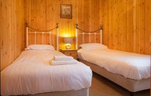two beds in a room with wooden walls at Yew Tree Lodge in Minehead
