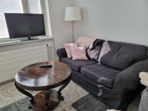 a living room with a black couch and a table at Studio Porin Oksi, home away home in Pori city center, free parking in Pori
