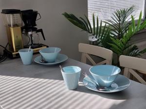 trois tasses et soucoupes sur une table avec une cafetière dans l'établissement Studio Porin Oksi, home away home in Pori city center, free parking, à Pori