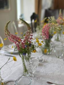 einen Tisch mit mehreren Vasen mit Blumen darin in der Unterkunft Magnor House in Eidskog, Hedmark close to The Plus and Magnor Glassverk in Magnor