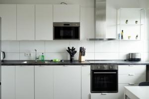 una cucina con armadi bianchi e piano cottura di Möblierte 3-Zimmer-Wohnung nahe Düsseldorf in Duisburg-Süd a Duisburg