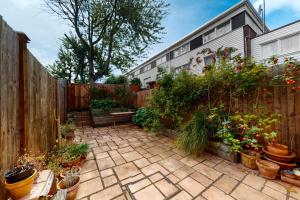 a garden with potted plants and a wooden fence at 3bed house with patio & parking - 9 min to Station in London