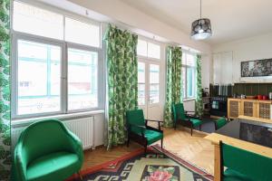 uma sala de estar com cadeiras verdes e janelas em INOLA Sunny flat with balcony in central Tbilisi em Tbilisi