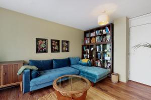 uma sala de estar com um sofá azul e uma estante de livros em 3bed house with patio & parking - 9 min to Station em Londres
