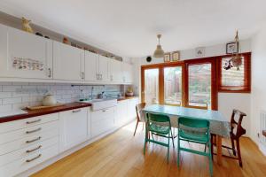 uma cozinha com armários brancos e uma mesa azul em 3bed house with patio & parking - 9 min to Station em Londres
