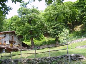 una antigua casa de piedra con una valla y árboles en agriturismo il riccio, en Cedegolo