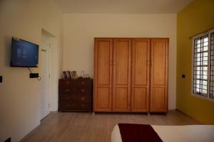 a bedroom with wooden cabinets and a dresser and a television at AKKANDI VEEDU FAIRY FALLS BY XACRO STAYS in Kodaikānāl