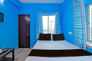 una camera blu con un letto e una finestra di OYO ANA GUEST HOUSE a kolkata