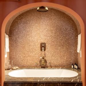 a bath tub in a bathroom with a brick wall at The Notary in Bruges