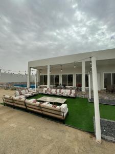 ein großes Gebäude mit Stühlen und grünem Rasen in der Unterkunft Rashed Farm in Al Rahba