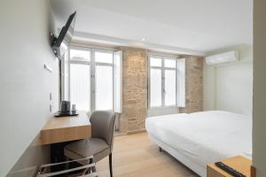 um quarto com uma cama e uma secretária com uma cadeira em Hotel Praza Quintana em Santiago de Compostela