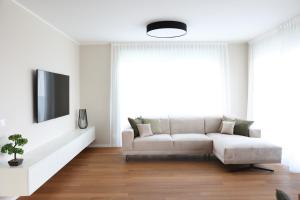 a white living room with a couch and a tv at VILLA MARIS SMRIKA -heated pool in Šmrika