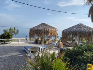 a group of chairs and straw umbrellas on the beach at ILIOPOULOS Apartments in Mourteri