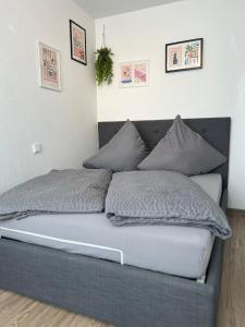 uma cama com almofadas cinzentas num quarto em Rosengarten Apartments in Tettnang em Tettnang