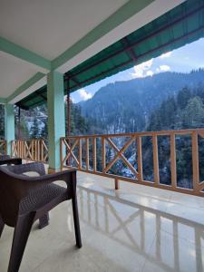 a balcony with a chair and a view of a mountain at The Forest Pinnacle and Café, Jibhi in Jibhi