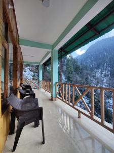 uma varanda com cadeiras e vista para uma montanha em The Forest Pinnacle and Café, Jibhi em Jibhi