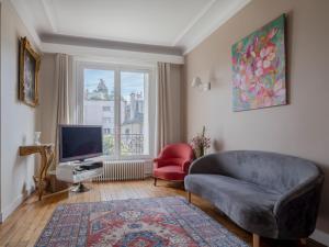 een woonkamer met een bank en een televisie bij Paris South Garden Residence in Saint-Cloud