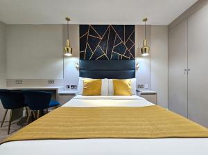 a bedroom with a large bed with yellow pillows at NOX Hyde Park in London