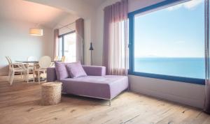 a living room with a purple couch and a large window at BYPILLOW Cap Sa Sal in Begur