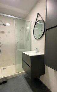 een badkamer met een wastafel en een douche met een spiegel bij Refuge au Cœur de La Baule in La Baule